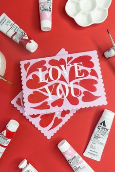 some crafting supplies are laying out on a red surface with the words love you