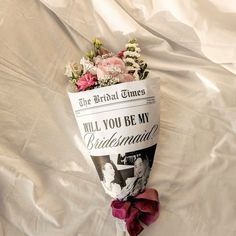 a bouquet of flowers is laying on a sheet with the words, will you be my bridesmaid?