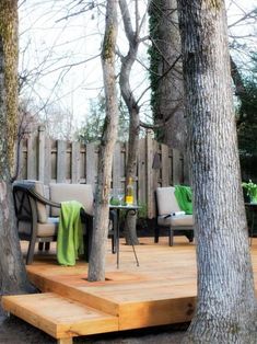 a wooden deck surrounded by trees and chairs