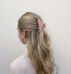 a woman with long blonde hair and a pink bow in her hair, wearing a white sweater