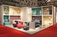 a room filled with lots of furniture on display in front of a red carpeted floor