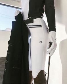 a mannequin dressed in white and black holding a coat over his shoulder while standing next to a window