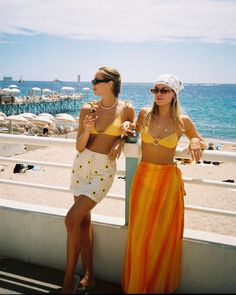 two women standing next to each other on a beach