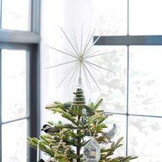 a small christmas tree with ornaments on it in front of a window and a starburst hanging from the top