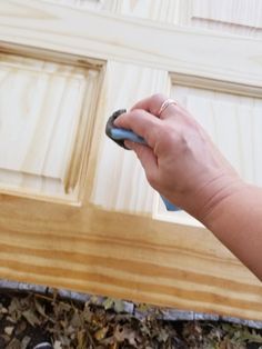 a person holding a remote control in their hand next to a wooden door with wood slats