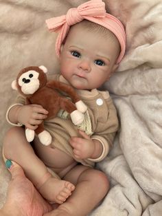 a baby girl holding a teddy bear in her hands