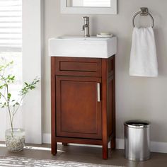 a white sink sitting under a mirror next to a wooden cabinet