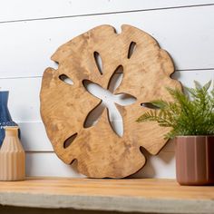 a wooden cutout on the side of a wall next to two vases and a potted plant