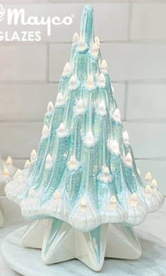 a glass christmas tree with white lights on it's base and the words mayoco glazes above it