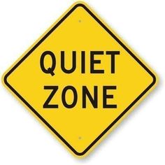 a yellow quiet zone sign with the words quiet zone written in black ink on it