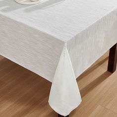 a white table cloth on top of a wooden table with a cup and saucer