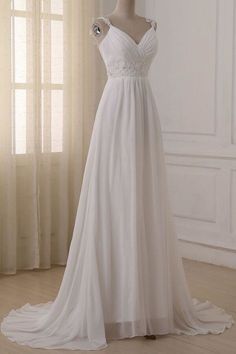 a white wedding dress on a mannequin in front of a curtained window