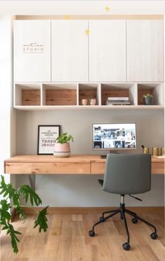 a desk with a computer and some plants on it in front of a white cabinet