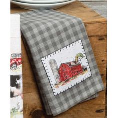 a kitchen towel with a farm scene on it next to a white plate and fork