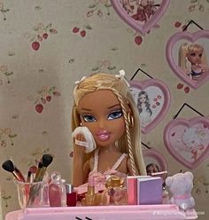 a barbie doll sitting at a table with makeup and other items on top of it