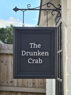 a sign hanging from the side of a building that says the drunken crab on it