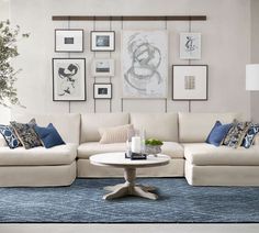 a living room with white couches and blue rugs on the floor in front of pictures