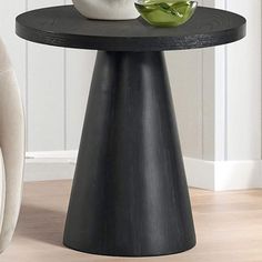 a black table with a green vase on it and a white chair in the background