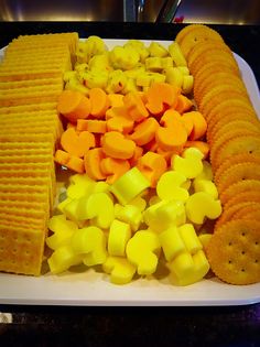 a platter with crackers, carrots and corn on it