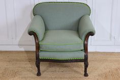 a green chair sitting on top of a hard wood floor next to a white wall