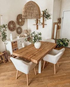 a dining room table with chairs and baskets hanging on the wall above it, along with potted plants