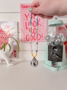 a person holding a beaded necklace next to a small machine and other items on a table