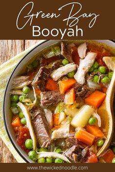 a bowl filled with beef and vegetables on top of a wooden table next to a spoon