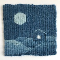 a knitted piece of fabric with a house in the background and a full moon