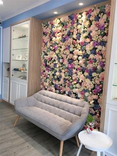 a living room with a flowered wall and grey couch in front of the tv