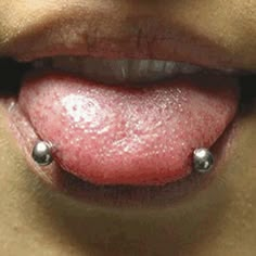 a woman's tongue with two balls attached to the top of her lip,