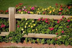 a wooden fence with flowers growing on it's sides and grass in the background