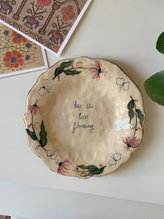 there is a plate with writing on it next to some pictures and a potted plant