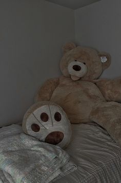 a large teddy bear laying on top of a bed next to a pillow and blanket