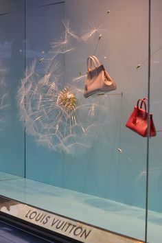 a display case with handbags and dandelions in the window for louis vuitton