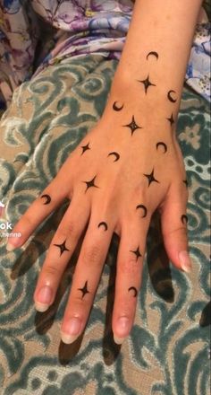 a woman's hand with stars and moon tattoos on it