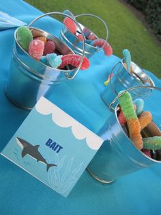 two buckets filled with candy sitting on top of a blue cloth covered tablecloth