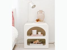 a white shelf with some books and a vase on it