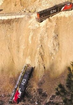 an aerial view of a train on the tracks near a mountain side with trees and rocks