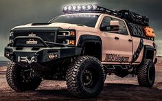 a white truck parked on top of a dirt field under a cloudy sky with lights