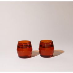 two red glasses sitting next to each other on a white surface