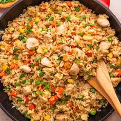 chicken fried rice in a skillet with wooden spoon