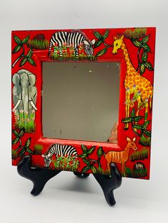 a red frame with zebras, giraffes and elephants painted on it