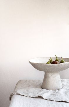 a white bowl filled with fruit on top of a table