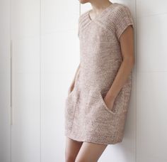 a woman leaning against a wall wearing a sweater dress