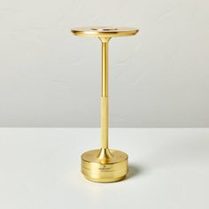 a gold candle holder on a white table with a plain background and no one around it