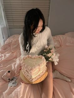 a woman sitting on top of a bed holding a cake