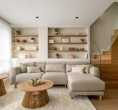 a living room filled with lots of furniture next to a stair case and wooden shelves