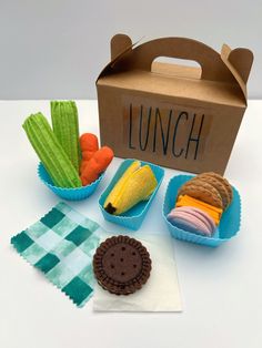 an open lunch box with cookies, carrots, celery and other food items