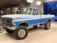 an old blue pickup truck parked in a garage