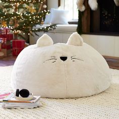 a large white bear pillow sitting on top of a rug next to a christmas tree